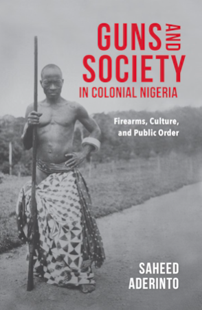 black-african man half naked staning on the left side with a spear and cultutral clothing, the clothing skirt is open on both side of legs. The man is position in a field on the right and standing on a plane sidewalk the tittle is on the upper right hand side